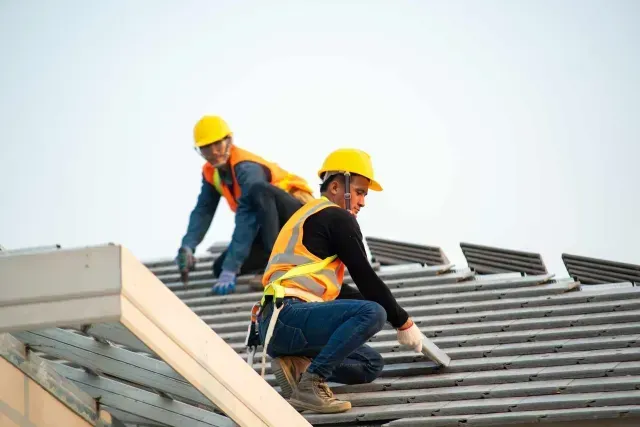 Two construction workers wearing safety vests and hard hats for new roof installation in Aurora, IL.